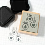 Drei Weihnachtskugeln, je eine mit Stern, Herz und Tannenbaum, die per Lasercut als Stempel graviert wurden.