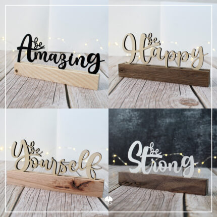 Es sind die Klötzchenwörter 'be Strong', 'be Amazing', 'be Yourself' und 'be Happy' zu sehen. Die Schriftzüge bestehen aus Papier und Sperrholz. Sie wurden zwischen zwei Klötzchen geklebt.