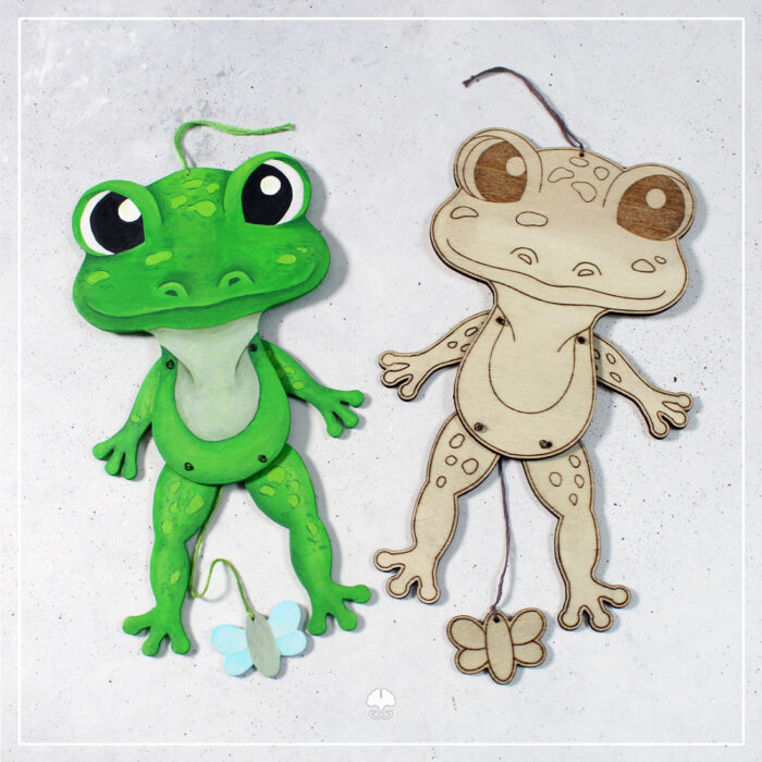 Zwei Varianten der Datei Hampelbauernhof "Frosch" aus Holz. Eine wurde mit dem Laser graviert und geschnitten. Die andere wurde mit der Laubsäge ausgesägt und dann mit Acrylfarben bemalt.