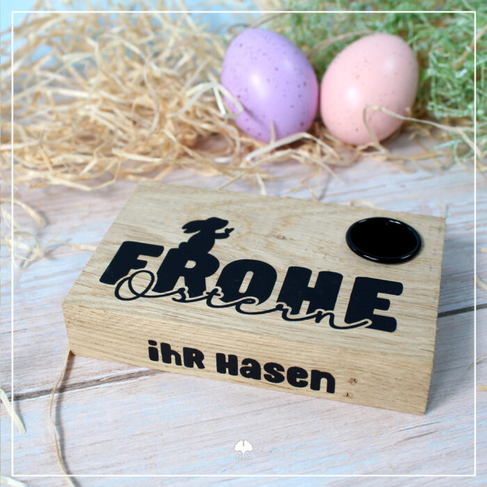 Abgebildet ist ein Beispiel zur Umsetzung der Datei Ostern "Hase mit Herz". Zu sehen ist ein Klötzchen (Dicke Dinger) als Kerzenhalter für Stabkerzen. Das Holz wurde mit "Frohe Ostern ihr Hasen" aus Flexfolie beplottet. Auf dem R von 'Frohe' ist ein Hase mit Herz.