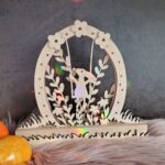 Ein Mini-Lichterbogen aus drei Ebenen mit Klötzchen kombiniert. Das Motiv zeigt einen Hasen auf einer Schaukel in einer Ei-Silhouette im Gras. Die Motive wurden aus Holz mit dem Laser geschnitten.