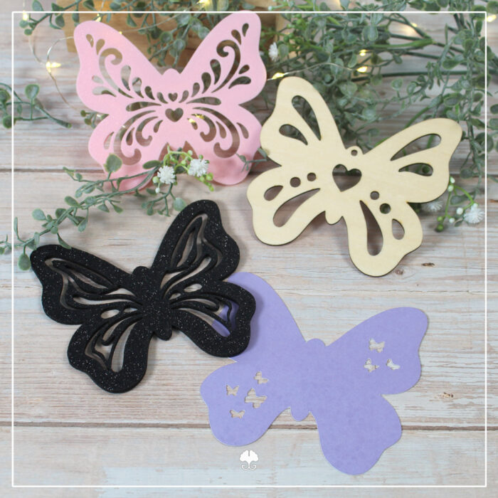 Verschiedenen Varianten der Schmetterlinge aus der Datei Mix'n Match "Schmetterlingsliebe". Sie wurden aus Sperrholz und Glitzerfilz gelasert, aus Papier mit dem Plotter geschnitten und aus rosa Filament mit dem 3D-Drucker gedruckt.