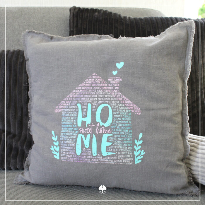 Ein Kissen wurde mit verschiedenen Flexfolien gestaltet. Abgebildet ist das Wortspiel "Home sweet Home" in rosa und türkisen Farbtönen.