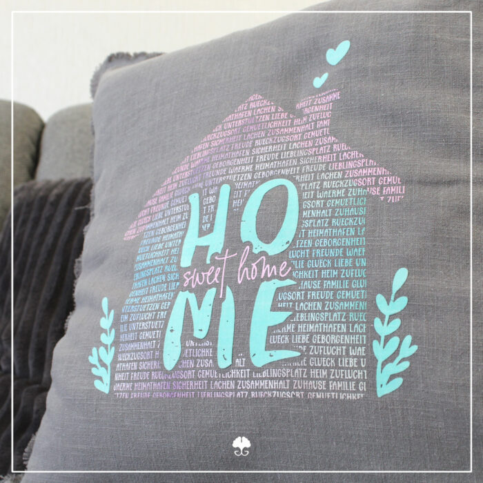 Ein Kissen wurde mit verschiedenen Flexfolien gestaltet. Abgebildet ist das Wortspiel "Home sweet Home" in rosa und türkisen Farbtönen.
