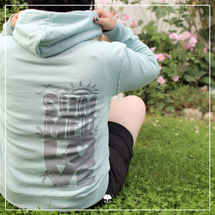Ein türkisfarbener Hoodie wurde mit dem Lettering "Summerlove" in grau auf dem Rücken beplottet.