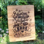 Beispiel für die Datei Lettering "Blumen lächeln". Der Spruch wurde mit dem Laser auf ein Schild aus Klötzchen graviert.