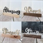 Es sind die Klötzchenwörter 'be Strong', 'be Amazing', 'be Yourself' und 'be Happy' zu sehen. Die Schriftzüge bestehen aus Papier und Sperrholz. Sie wurden zwischen zwei Klötzchen geklebt.