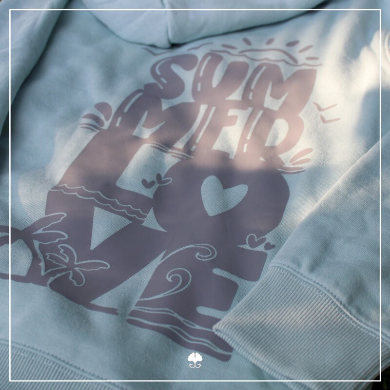 Ein türkisfarbener Hoodie wurde mit dem Lettering "Summerlove" in grau auf dem Rücken beplottet.