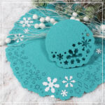 Ein winterlicher Untersetzer aus Filz. In zwei unterschiedlichen Größen. Mit dem Laser wurden darauf viele verschiedene Schneeflocken und Sterne graviert. Diese sind beim Großen als Ring am äußeren Rand angeordnet. Beim kleinen sind nur einzelne Motive an einer Seite. Einige der Schneeflocken wurden außerdem aus Glitzerfolie mit dem Plotter geschnitten und verpresst.