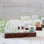 Abgebildet sind die drei Schriftvarianten der 3D Klötzchenschrift "Mr & Mrs" für unterschiedliche Buttongrößen. Sie wurden aus weißem und pfirsich-farbenem Silk-Filament gedruckt und mit dunklen Klötzchen kombiniert.